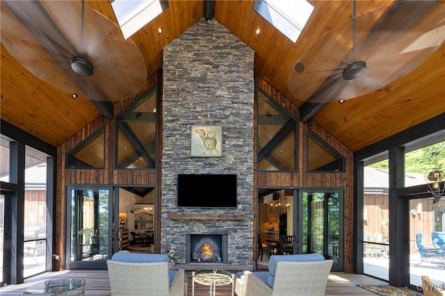 living room with a skylight, wood ceiling, a stone fireplace, and wood finished floors