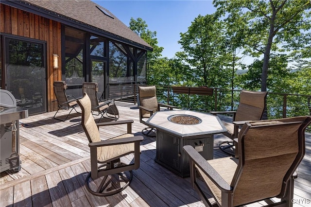 deck featuring an outdoor fire pit and a sunroom