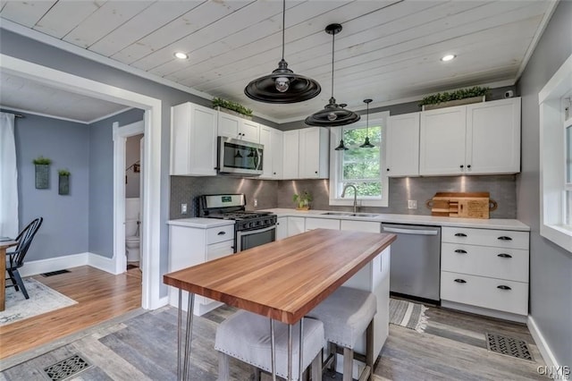 kitchen with white cabinets, light wood-style flooring, stainless steel appliances, crown molding, and a sink