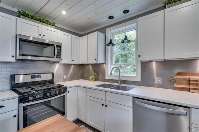 kitchen with a sink, white cabinets, appliances with stainless steel finishes, tasteful backsplash, and decorative light fixtures