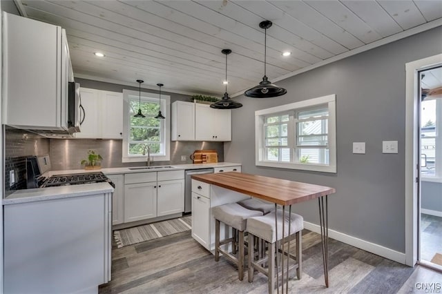 kitchen with appliances with stainless steel finishes, white cabinetry, a sink, and tasteful backsplash