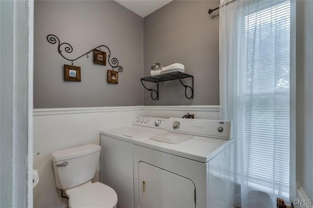 bathroom with toilet, a wealth of natural light, and independent washer and dryer