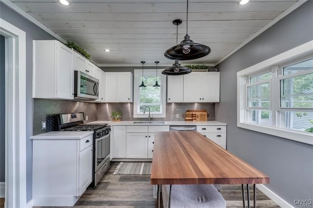 kitchen with baseboards, a sink, stainless steel appliances, white cabinetry, and backsplash