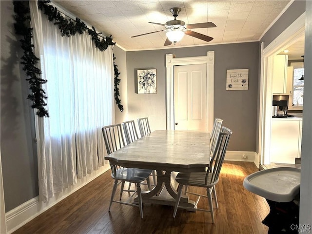 dining area featuring dark wood-style floors, baseboards, ornamental molding, and ceiling fan