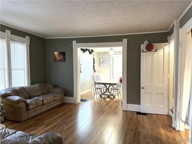 living room featuring baseboards, visible vents, ornamental molding, and wood finished floors