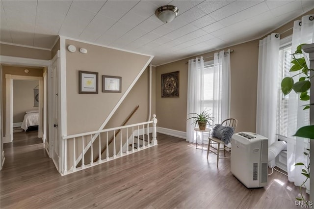 sitting room with baseboards, crown molding, an upstairs landing, and wood finished floors