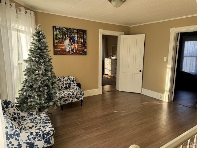 sitting room featuring baseboards, wood finished floors, and crown molding