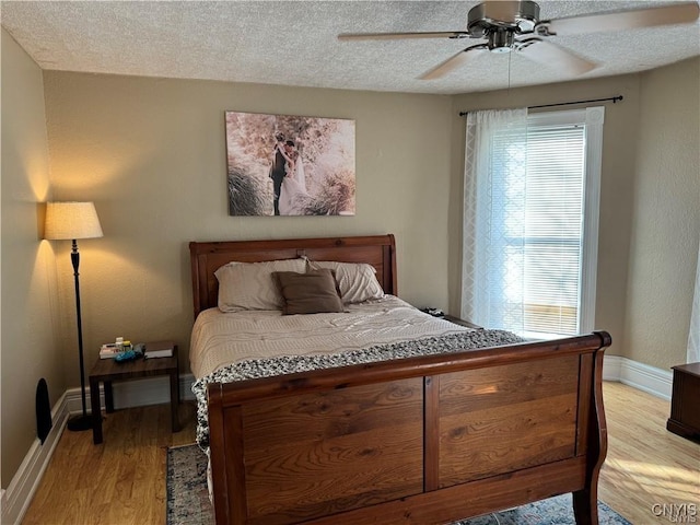 bedroom with light wood-style flooring, multiple windows, baseboards, and a textured ceiling