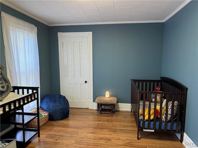 bedroom featuring crown molding, a closet, baseboards, and wood finished floors