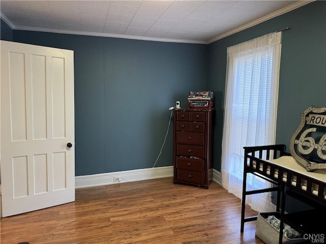 bedroom featuring crown molding, baseboards, and wood finished floors