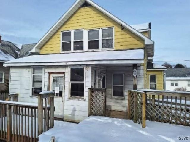 snow covered rear of property with a deck