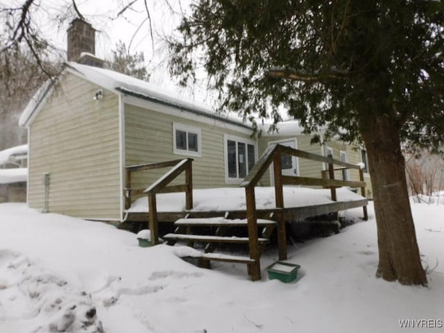 snow covered house with a wooden deck