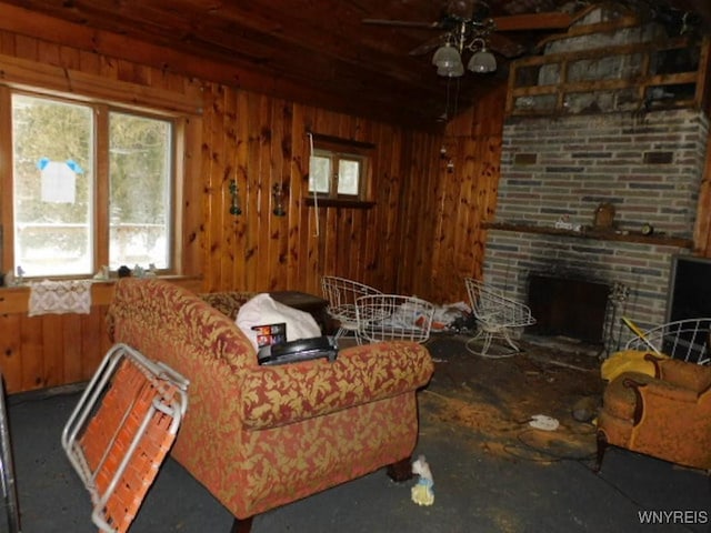 living room featuring a ceiling fan, a fireplace, and wooden walls