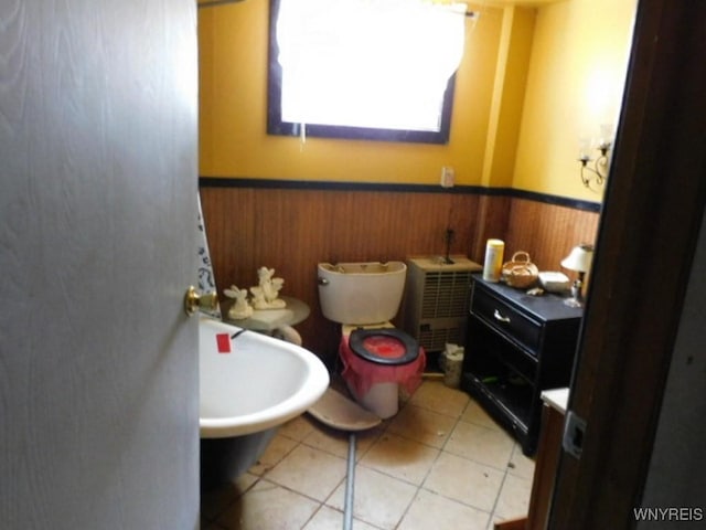 bathroom featuring a wainscoted wall, wooden walls, and tile patterned floors