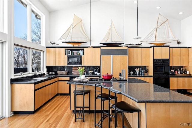 kitchen featuring a high ceiling, a sink, a kitchen island, decorative backsplash, and black appliances