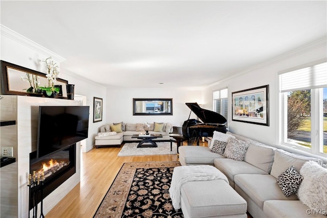 living area with crown molding, a glass covered fireplace, and light wood-style floors