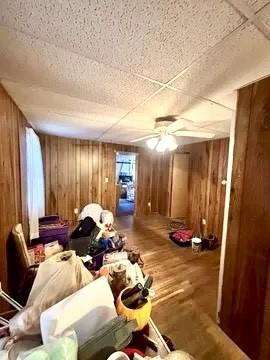 interior space with wood finished floors, a ceiling fan, and wooden walls