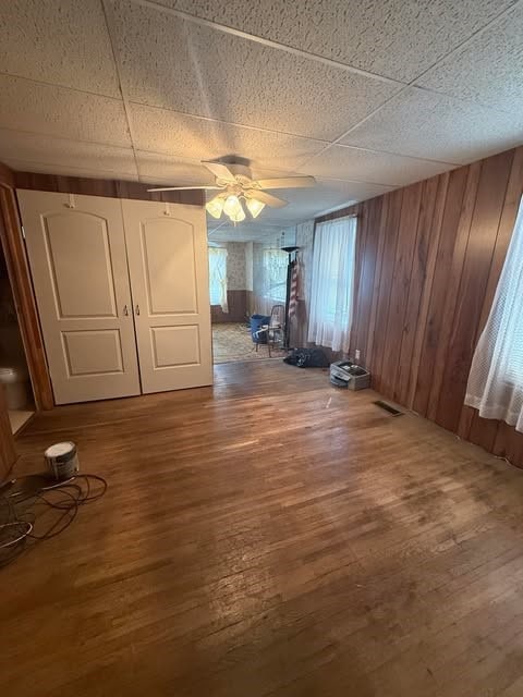 100 Cruger St, Bath, NY 14810 - interior space featuring visible vents, a ceiling fan, wood finished floors, and wooden walls
