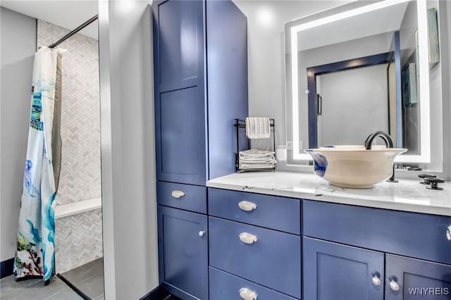 bathroom with tile patterned flooring, a tile shower, and vanity