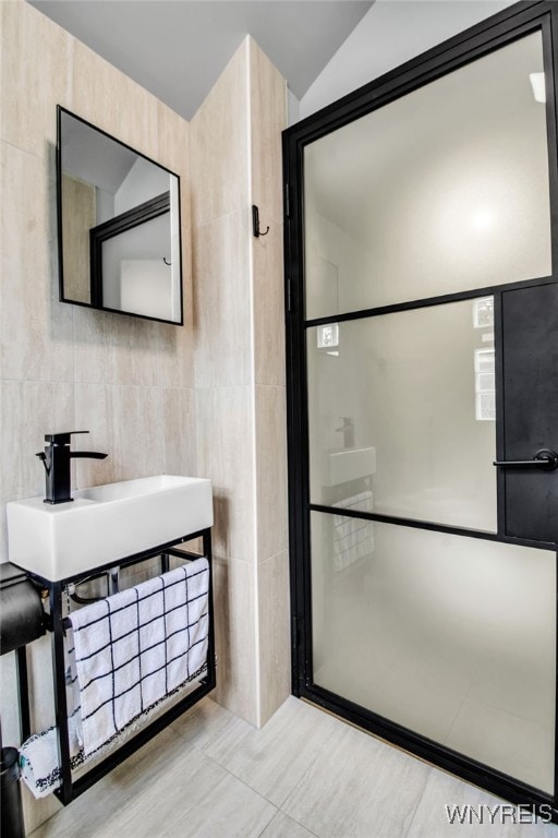 bathroom featuring a sink, vaulted ceiling, and tile walls