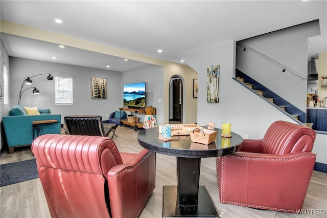 living room featuring arched walkways, stairway, recessed lighting, and wood finished floors