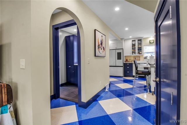 hall with dark floors, arched walkways, baseboards, and recessed lighting