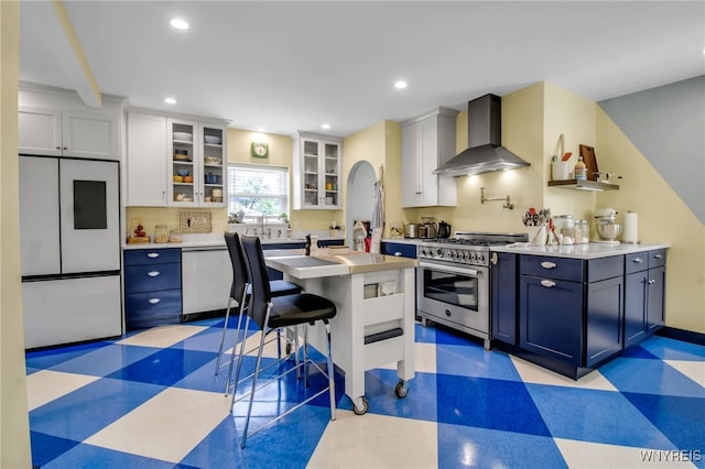 kitchen with light floors, stainless steel stove, dishwasher, wall chimney exhaust hood, and fridge