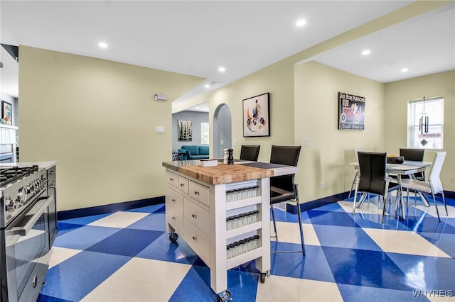 dining area featuring dark floors, arched walkways, baseboards, and recessed lighting