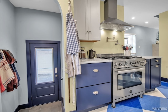 kitchen featuring light countertops, wall chimney range hood, high end stainless steel range oven, and baseboards