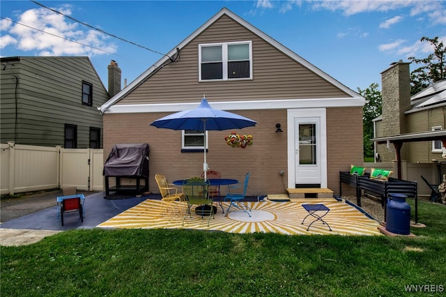 rear view of house with a patio area, fence, brick siding, and a lawn