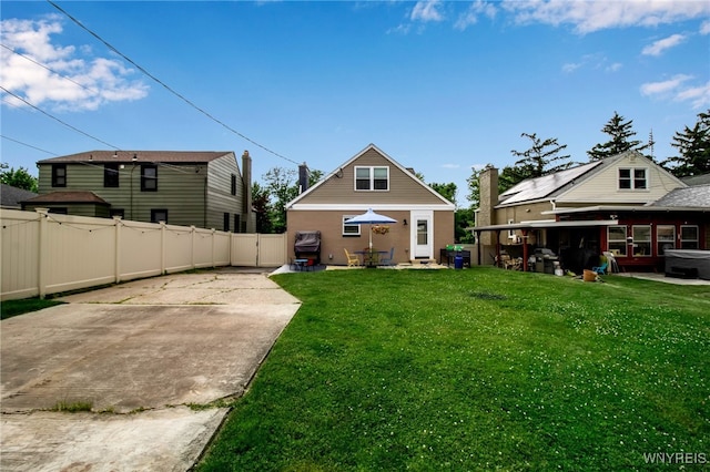 rear view of house with a patio, a lawn, and fence