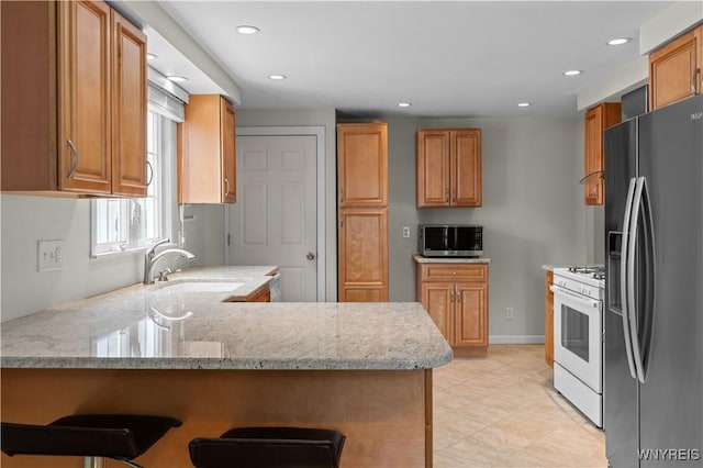 kitchen with stainless steel appliances, recessed lighting, a sink, light stone countertops, and a peninsula