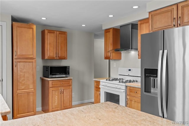 kitchen with baseboards, appliances with stainless steel finishes, brown cabinets, wall chimney range hood, and recessed lighting