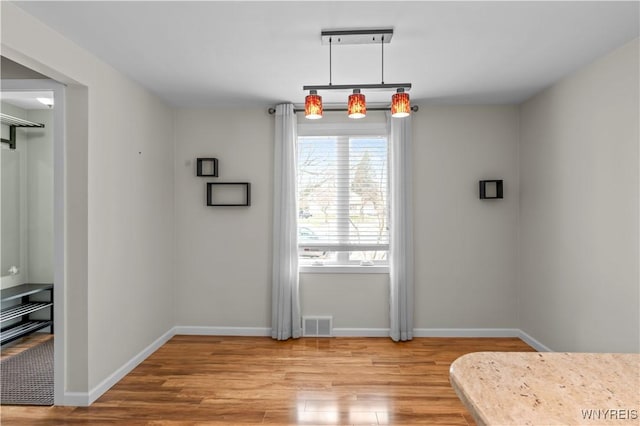 unfurnished dining area featuring baseboards, visible vents, and light wood-style floors