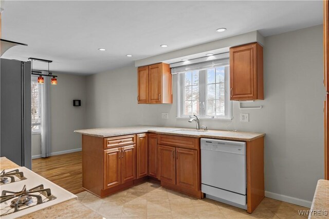 kitchen featuring white appliances, light countertops, a sink, and a peninsula