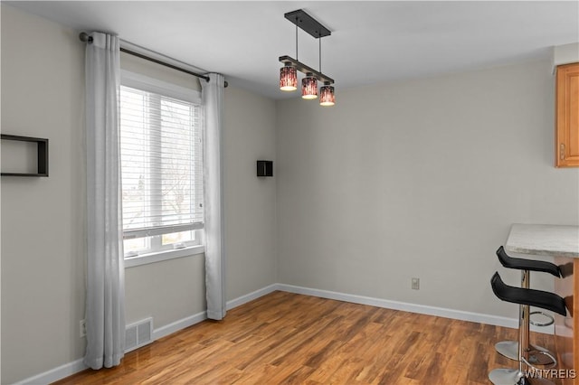 dining space featuring visible vents, light wood-style flooring, and baseboards