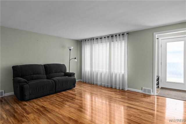 living area featuring wood finished floors, visible vents, and baseboards