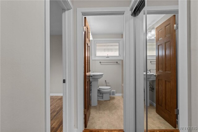 half bath featuring toilet, visible vents, and baseboards