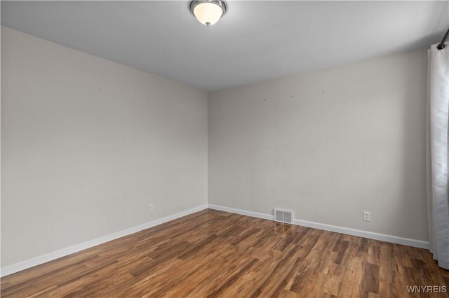 spare room with visible vents, baseboards, and wood finished floors