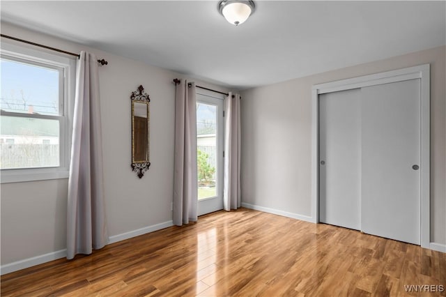 unfurnished bedroom featuring a closet, light wood-style flooring, and baseboards