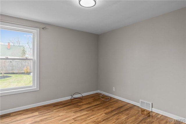 empty room featuring baseboards, visible vents, and light wood finished floors