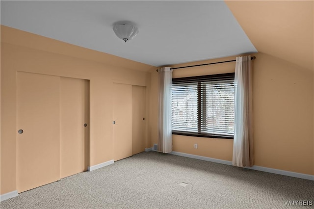 unfurnished bedroom with multiple closets, light colored carpet, and baseboards