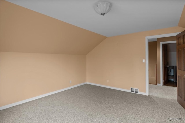 bonus room featuring light colored carpet, visible vents, vaulted ceiling, and baseboards