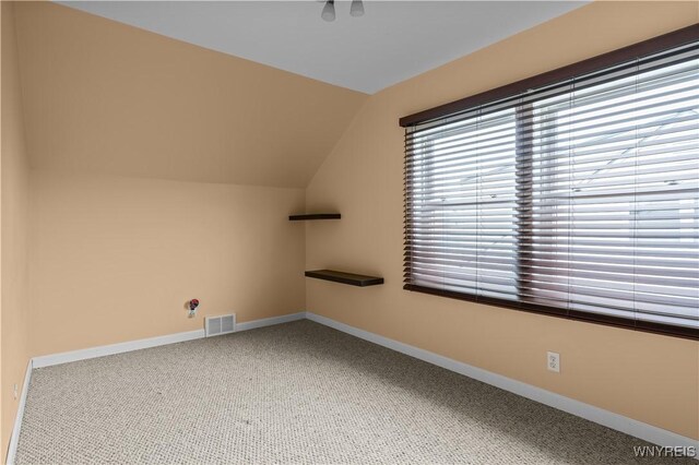 additional living space with vaulted ceiling, carpet flooring, visible vents, and baseboards