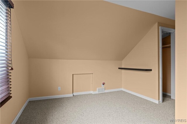 additional living space with lofted ceiling, baseboards, visible vents, and carpet flooring