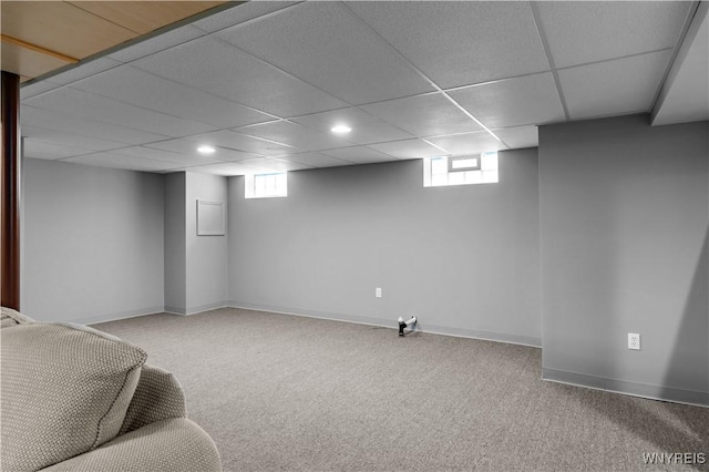 below grade area featuring carpet floors, a wealth of natural light, and a drop ceiling