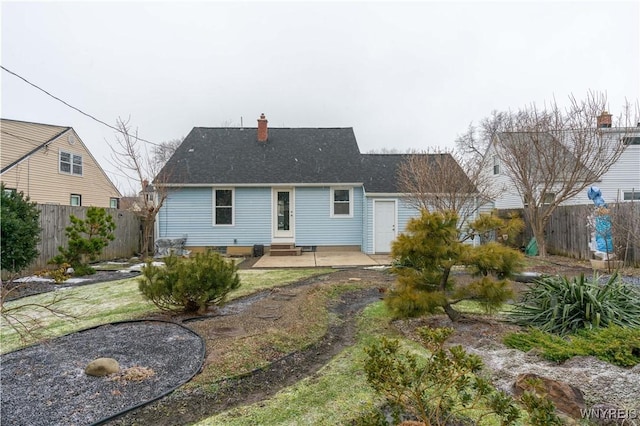 back of property with entry steps, a fenced backyard, a chimney, and a patio