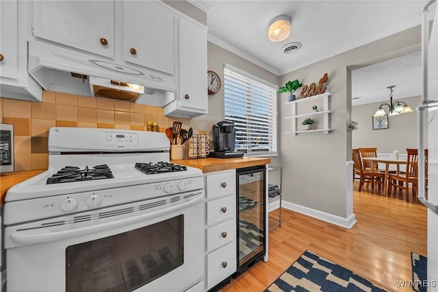 kitchen featuring white gas stove, visible vents, white cabinetry, beverage cooler, and under cabinet range hood