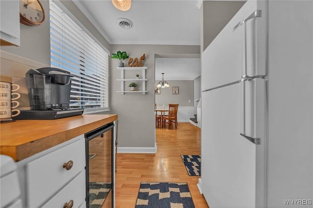 kitchen featuring beverage cooler, visible vents, freestanding refrigerator, an inviting chandelier, and light wood-type flooring