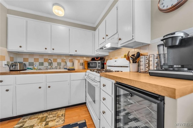 kitchen featuring wine cooler, ornamental molding, white range with gas cooktop, a sink, and under cabinet range hood